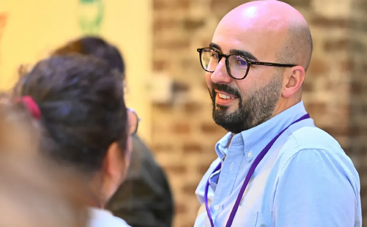 An attendee wearing a badge talks with other attendees
